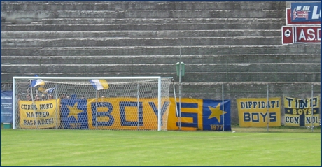 Alcuni tricolori blu-bianco-gialli sventolano dietro gli striscioni BOYS appesi in Curva: 'Curva Nord Matteo Bagnaresi', 'BOYS', 'Diffidati BOYS' e 'Tino con noi'