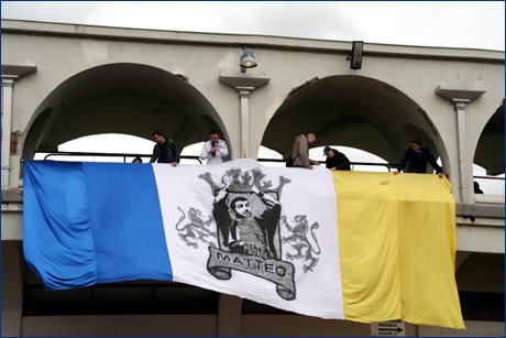 Striscione tricolore bianco-giallo-blu, con al centro il volto del Bagna