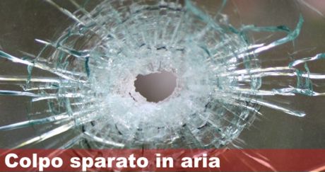 Un vetro forato da un proiettile e la scritta: colpo sparato in aria